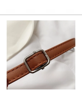 Detailed macro view of brown cross-grain leather strap with silver metal buckle