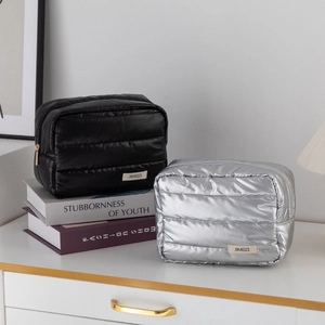 Close-up of quilted puff makeup bags in black and silver with sleek zipper detail