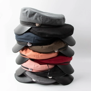 Vertical stack of multi-colored retro newsboy hats with leather brims and metal buttons