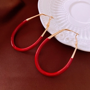 Vue détaillée des boucles d'oreilles en résine rouge avec détails en métal doré