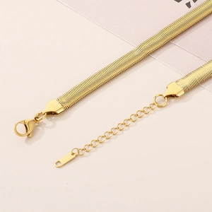 Detail of gold snake chain bracelet with adjustable lobster clasp on minimalist background