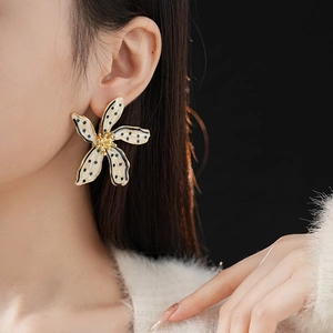 Macro view of vintage beige floral earrings with black polka dots on model