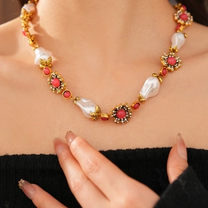 Detailed close-up of vintage flower necklace with red gemstone and pearls on model