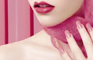 Close-up of matching pink lipstick and nail polish applied on model with soft scarf