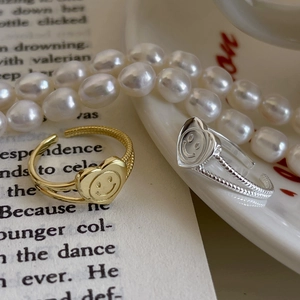 Detailed view of silver and gold heart smile rings with twisted rope bands on a book