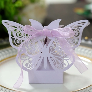 Detailed macro view of laser-cut butterfly wedding favor box with purple ribbon