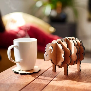 Close-up of sheep shaped wooden coaster set with petal-shaped mats on a sunny table