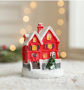 Vue détaillée d'une mini maison de Noël en résine rouge avec toit enneigé et sapin nain
