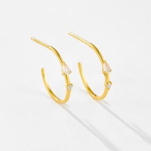 Macro detail of 925 silver C-shape gold earrings with teardrop opal and round diamond