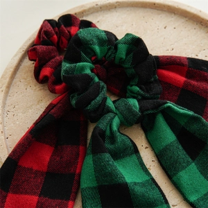 Detail of red and green plaid velvet scrunchies with ribbons on a stone tray