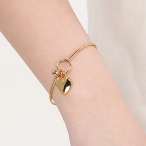 Close-up of a minimalist gold stainless steel bracelet featuring a heart charm on wrist