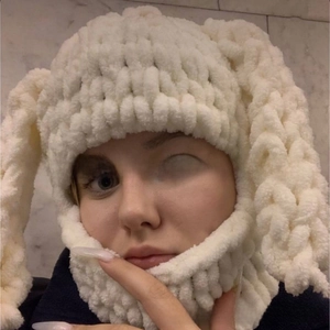 Detailed close-up of a chunky knit bunny ear balaclava in off-white winter wool fabric