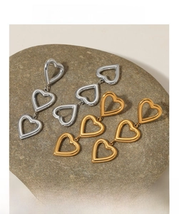 Vue détaillée de boucles d'oreilles cœur étagées en argent et or sur support pierre