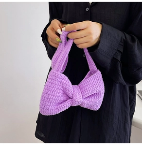 Détail du sac à bandoulière en tricot violet avec un grand nœud et texture gaufrée