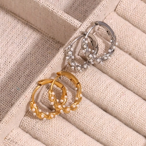Twisted gold and silver hoop earrings with white pearls in a jewelry display case