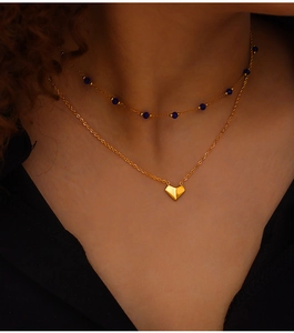 Double-layer gold necklace featuring blue crystal beads and a heart pendant on neck