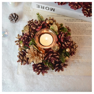 Macro detail of Christmas pine cone candle holder with gold accents and green foliage