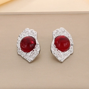 Detail view of red cat eye gemstone set in irregular silver-plated geometric earrings