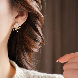 Detail of elegant gold-plated firework earrings with white pearls on a female model