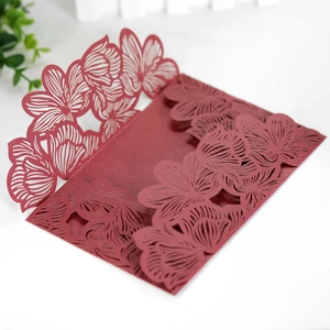 Detail of laser cut burgundy wedding invitation with intricate floral hollow pattern