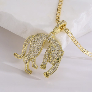 Gold leopard pendant necklace with pavé cubic zirconia and emerald eyes on marble background