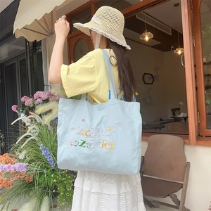 Gros plan sur la broderie Lucky Suzakka d'un sac cabas en toile bleu clair pour l'été