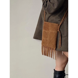 Caramel suede crossbody bag with fringe detail on model in vintage style outfit