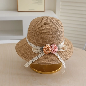 Detail of woven straw sun hat featuring elegant lace ribbons and delicate fabric flowers