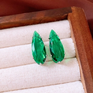 Macro detail of green teardrop faux gemstone earrings in a premium wooden jewelry box