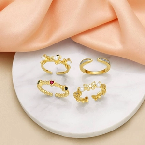 Set of four gold-plated adjustable rings with butterfly, flower, and pearl designs