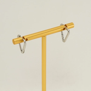 Minimalist silver stainless steel triangle huggie hoop earrings for women on a gold stand