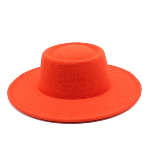 Detailed top view of a bright orange wool felt flat top hat with a wide stiff brim