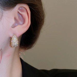Close-up of elegant gold pear-shaped earrings with micro-pave cubic zirconia on a model