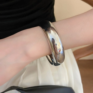 Gros plan d'un bracelet jonc épais en métal argenté poli avec finition miroir