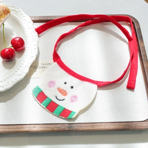 Detail of plush snowman accessory with festive embroidery and long red strap for pets