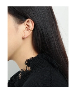 Detailed view of polished gold hoop earring and minimalist ear cuff set on a model ear