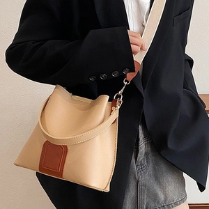 Chic beige and brown contrast bucket bag with wide fabric strap styled on a model