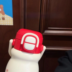 Close-up of the red insulated bottle showing its secure white safety lock feature