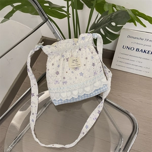 Detailed shot of quilted white crossbody bag with purple teddy bear and lace trim detail