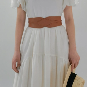 Detail of brown wide waist belt with geometric crisscross design on white dress