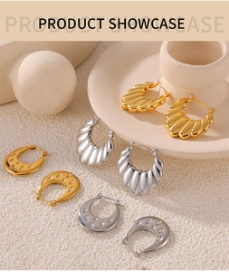 Close-up of gold and silver U-shaped hoop earrings with wavy textures on a ceramic dish
