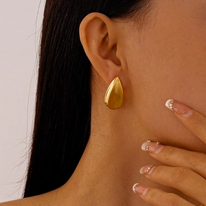 Gros plan détaillé d'une boucle d'oreille goutte en or mat portée par un mannequin chic