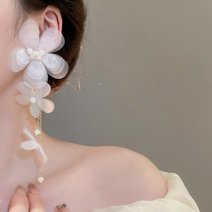 Detail of white chiffon flower earrings with pearl stamen and long metal chain tassels