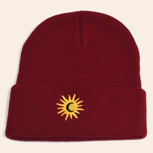 Detailed view of the sun and moon embroidery on a burgundy knit beanie cap