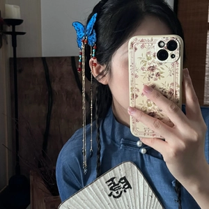 Détail de la pince à cheveux papillon bleu avec glands perlés sur le côté des cheveux
