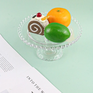 Round glass cake stand with beaded rim and base featuring fruit and dessert