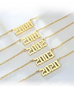 Vue détaillée de colliers d'année en acier inoxydable plaqué or 18K avec numéros gothiques