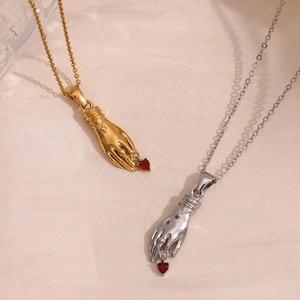Retro 18K gold plated hand pendant necklace with a red heart gem on silk background