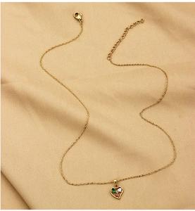 Close-up of heart-shaped gold necklace with green, red and white zircon stones
