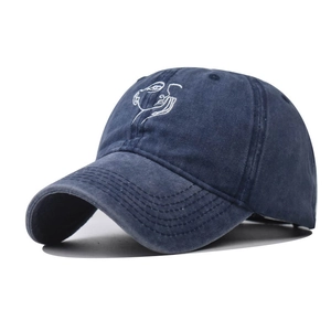 Dettaglio cappellino in cotone lavato blu scuro con ricamo minimalista di un volto bianco